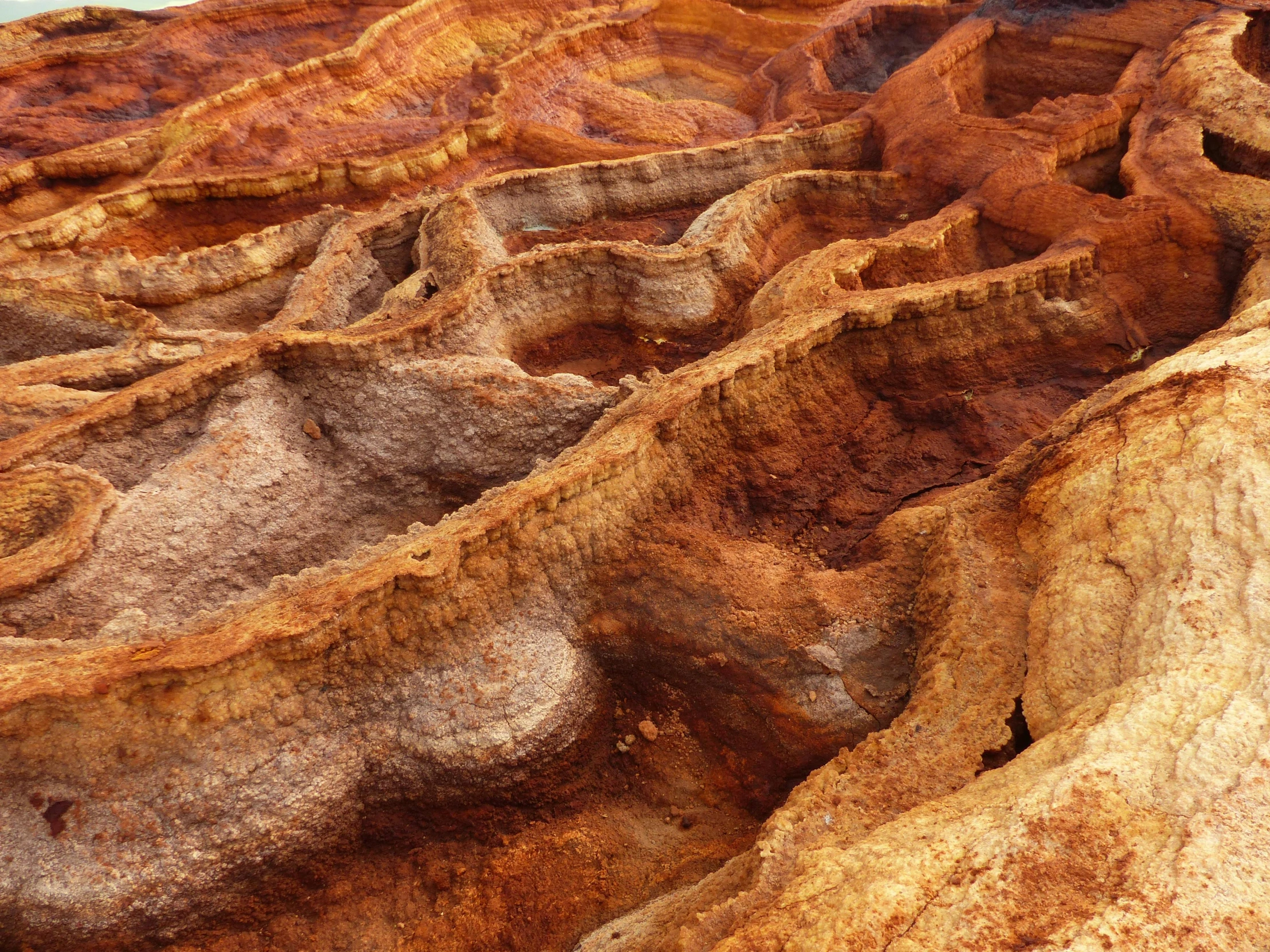 a large rock formation in the middle of a desert, pexels contest winner, australian tonalism, shiny layered geological strata, yellows and reddish black, bryce 3 d, bent rusted iron