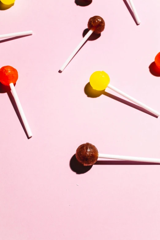 a bunch of lollipops sitting on top of a pink surface, profile image, caramel, photographed for reuters, red yellow