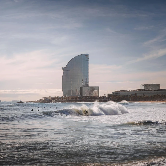 a man riding a wave on top of a surfboard, by Daniel Seghers, pexels contest winner, hyperrealism, brutalist buildings tower over, fc barcelona, curvy build, grain”