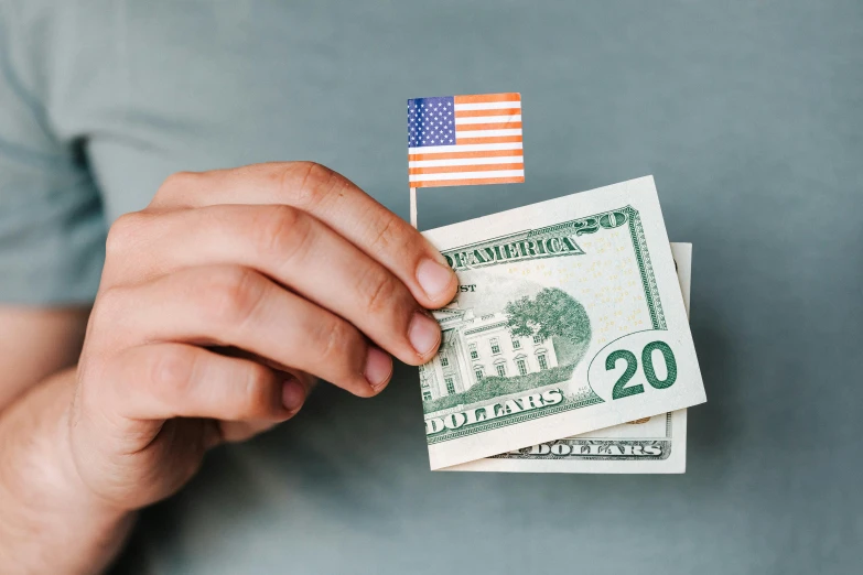 a man holding a stack of money with an american flag sticking out of it, pexels contest winner, 🚿🗝📝