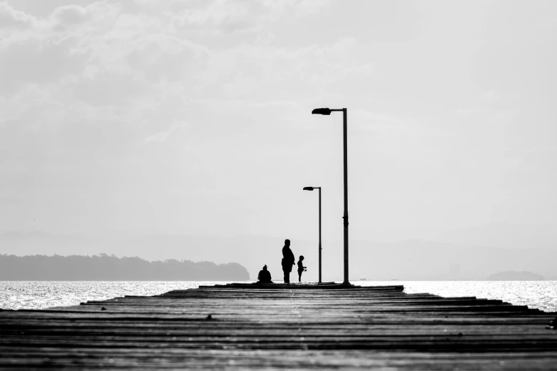 a black and white photo of two people standing on a pier, by Niko Henrichon, pexels contest winner, minimalism, sittin, contre jour, two old people, lights on