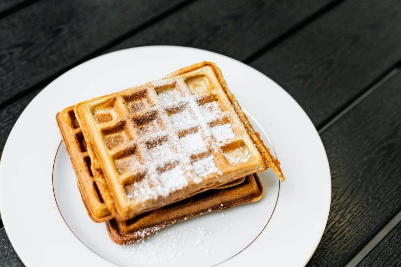 a white plate topped with waffles covered in powdered sugar, by Niko Henrichon, unsplash, square, brown, 🚿🗝📝