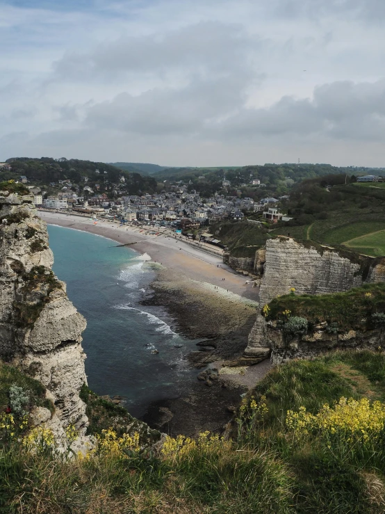 a man standing on top of a cliff next to the ocean, by Raphaël Collin, pexels contest winner, renaissance, normandy, panorama of crooked ancient city, marsden, beach in the foreground