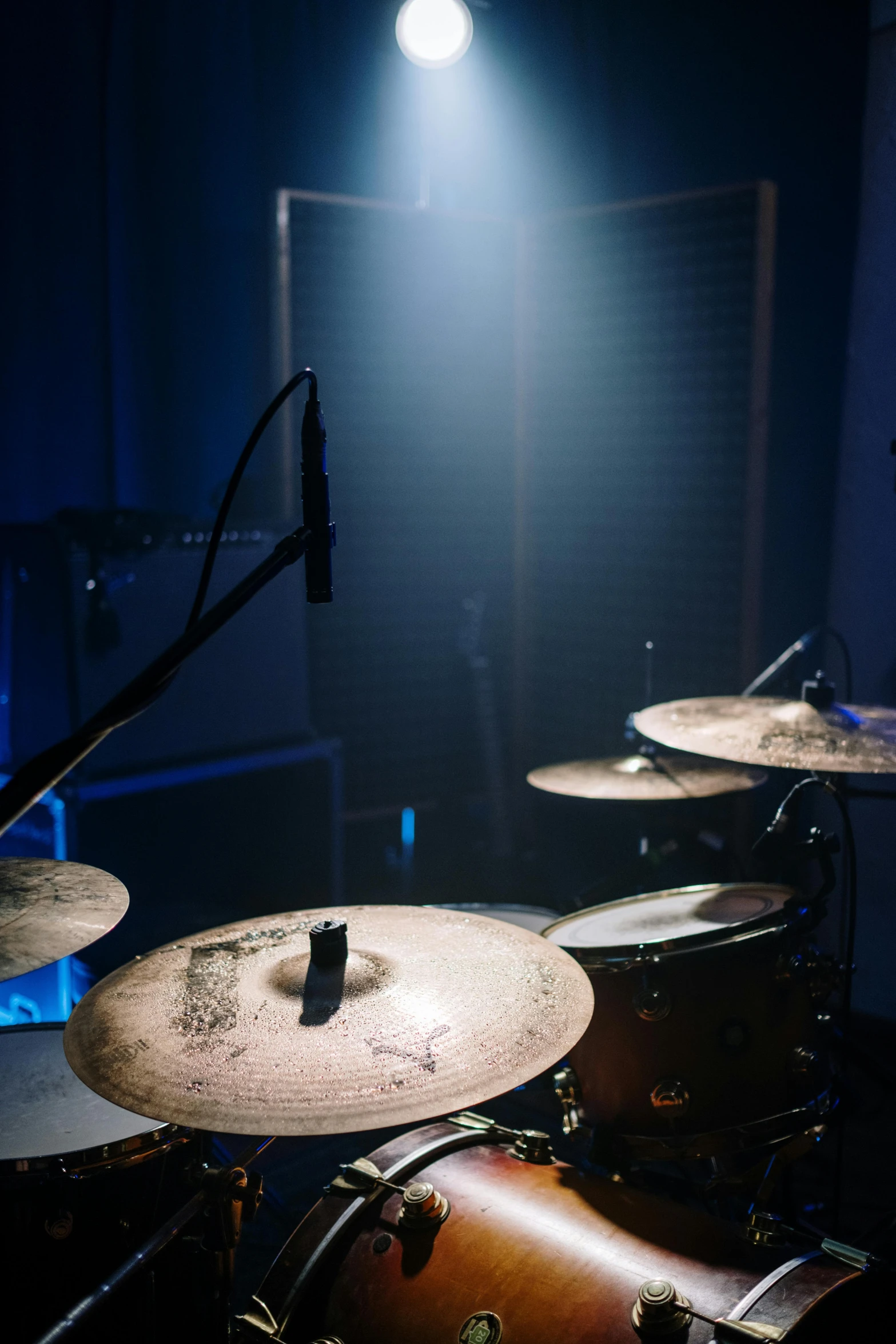 a drum set up in a dimly lit room, an album cover, pexels contest winner, light and space, blue, under studio lighting, indoor picture, video footage