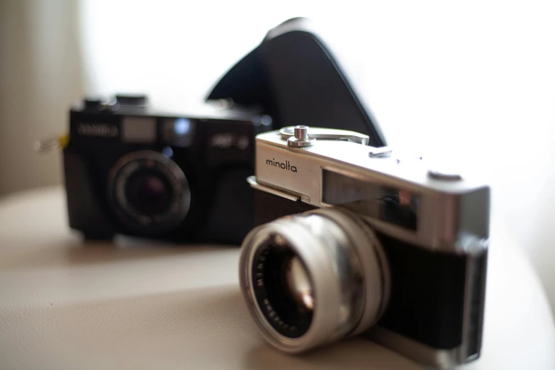 a couple of cameras sitting on top of a table, a picture, inspired by Vivian Maier, unsplash, medium format. soft light, colour photograph, close-up photograph, 3 / 4 extra - wide shot