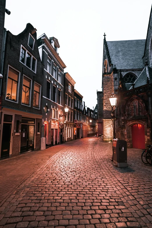 a cobblestone street is lit up at night, by Daniel Seghers, gothic revival, red lights, during dawn, dutch