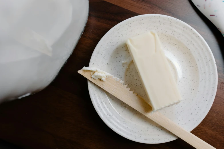 a piece of cake sitting on top of a white plate, by Jessie Algie, unsplash, process art, plenty mozzarella, on a wooden tray, butter, off-white plated armor