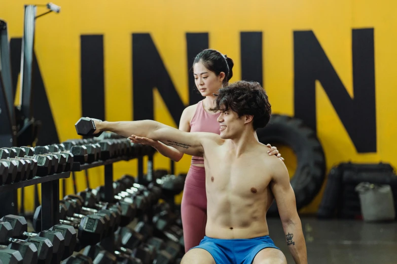 a man sitting next to a woman in a gym, by Natasha Tan, unsplash, realism, wearing yellow croptop, thumbnail, background image, hong soonsang