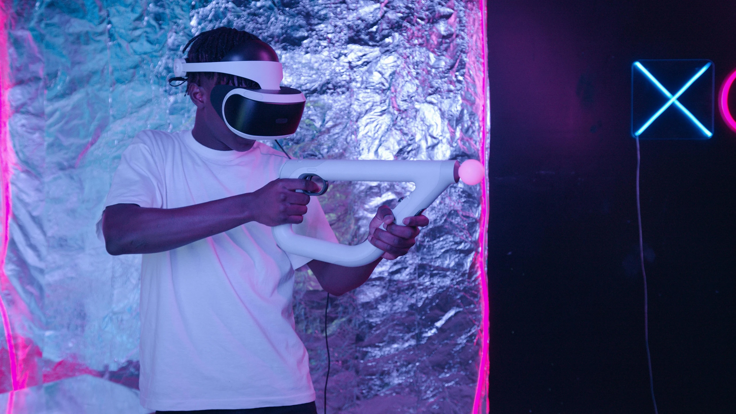 a man in a white shirt holding a video game controller, a hologram, inspired by David LaChapelle, unsplash, interactive art, : kanye west wearing vr goggles, closed limbo room, shot with sony alpha 1 camera, purple ambient light