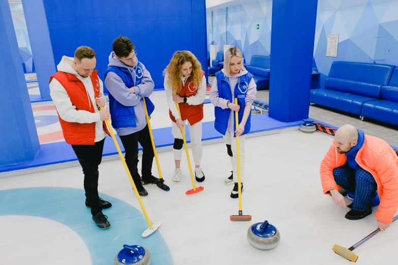 a group of people standing around a curling rink, dasha taran, game, ice blue, abcdefghijklmnopqrstuvwxyz