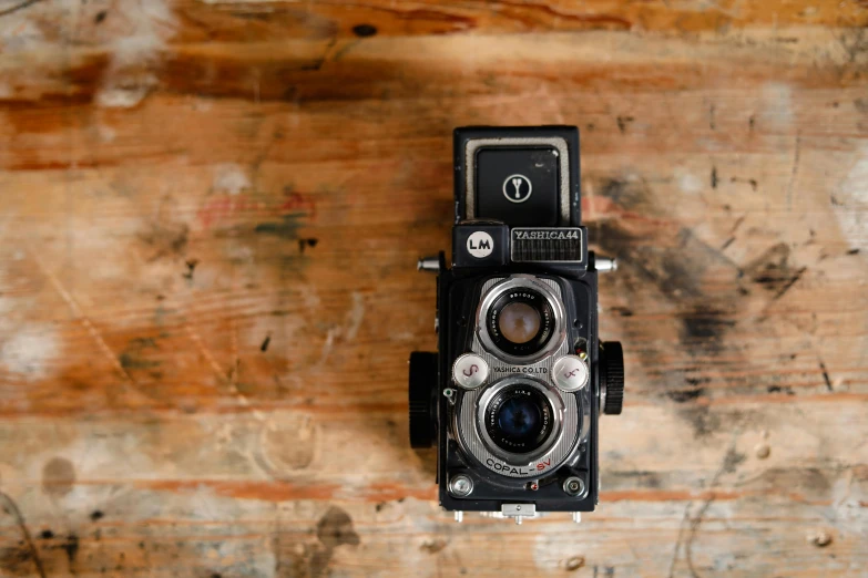 an old camera sitting on top of a wooden table, by Sven Erixson, unsplash, rolleiflex tlr, rectangle, black, brown