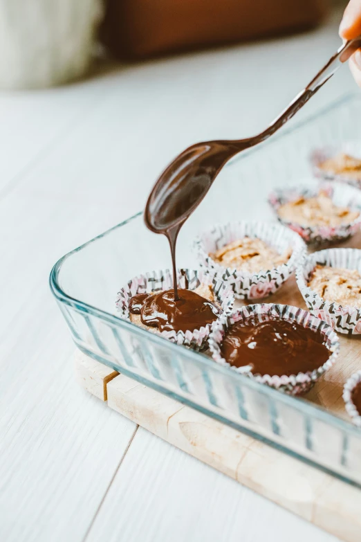 a tray of cupcakes being drizzled with chocolate, by Lucette Barker, trending on unsplash, bowl, manuka, wide high angle view, half image