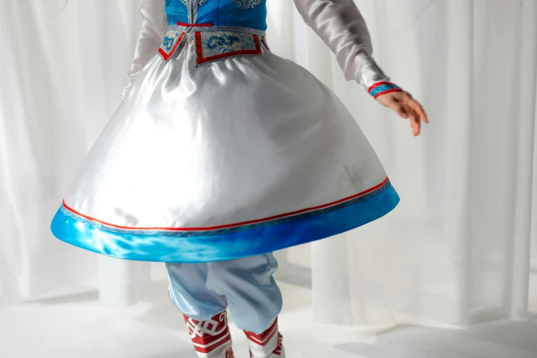 a woman in a blue and white dress is dancing, an album cover, inspired by Jean-Étienne Liotard, unsplash, arabesque, inuit heritage, silver red white details, on a mannequin. high resolution, close-up on legs