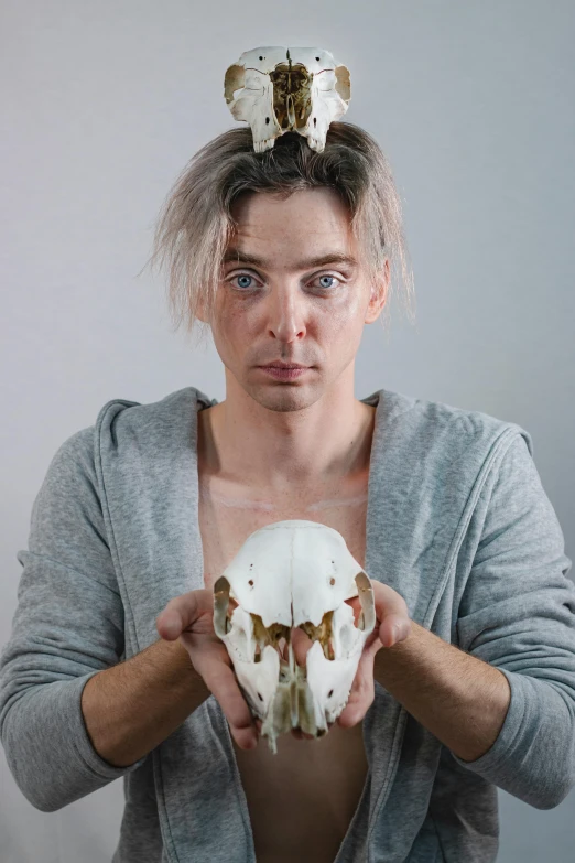 a man holding a skull in front of his face, a character portrait, inspired by Alexander Kanoldt, non-binary, looking like a bird, quicksilver, production photo