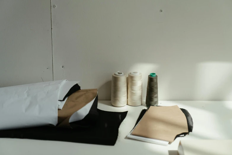 a bunch of sewing supplies sitting on top of a table, inspired by Alberto Burri, leather clothing, white wall coloured workshop, detached sleeves, dark and beige atmosphere