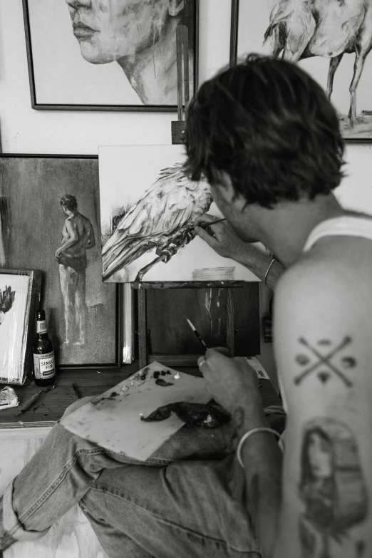 a man sitting on a bed with a tattoo on his arm, by Jessie Alexandra Dick, process art, with the beak of an eagle, painting a canvas, davide sorrenti, tending on art station