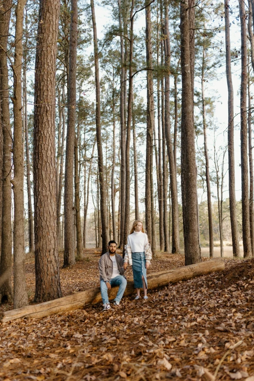 a man and a woman sitting on a log in the woods, a portrait, by Kristin Nelson, pexels contest winner, sparse pine trees, tall broad oaks, rectangle, brown