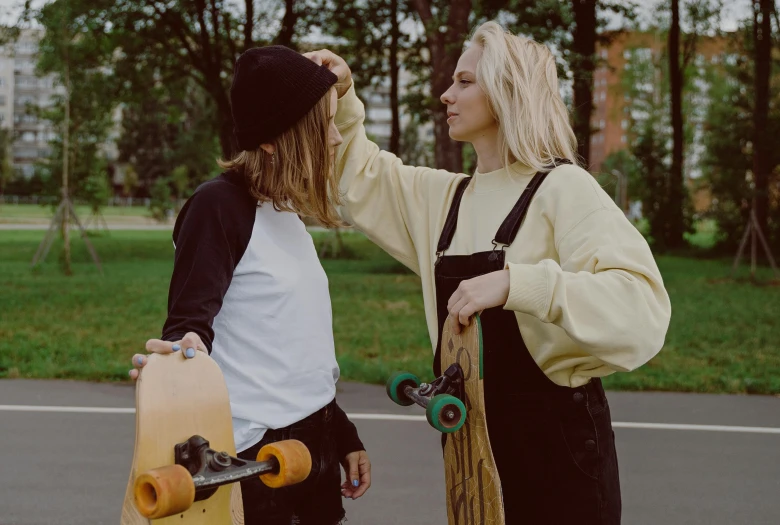 a couple of women standing next to each other holding skateboards, a photo, by Emma Andijewska, trending on pexels, profile pic, rated t for teen, looking at each other mindlessly, 15081959 21121991 01012000 4k