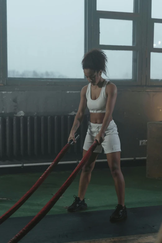 a woman working out with a rope in a gym, an album cover, by Adam Marczyński, pexels contest winner, ashteroth, video still, cold, ( ( theatrical ) )