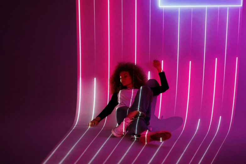 a woman sitting on a skateboard in front of a neon wall, inspired by Richard Anuszkiewicz, pexels contest winner, interactive art, brightly lit pink room, imaan hammam, laying down, 3d style light refraction