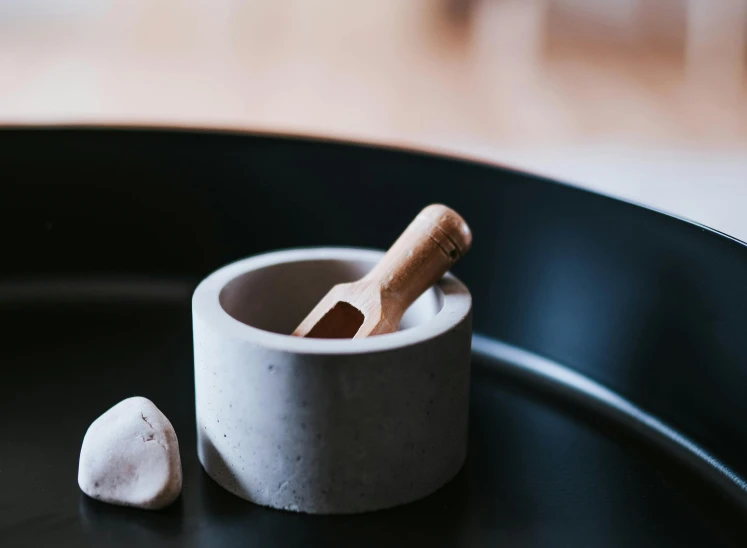 a mortar and a wooden spoon on a black plate, a marble sculpture, trending on pexels, apothecary, joints, white, opening shot