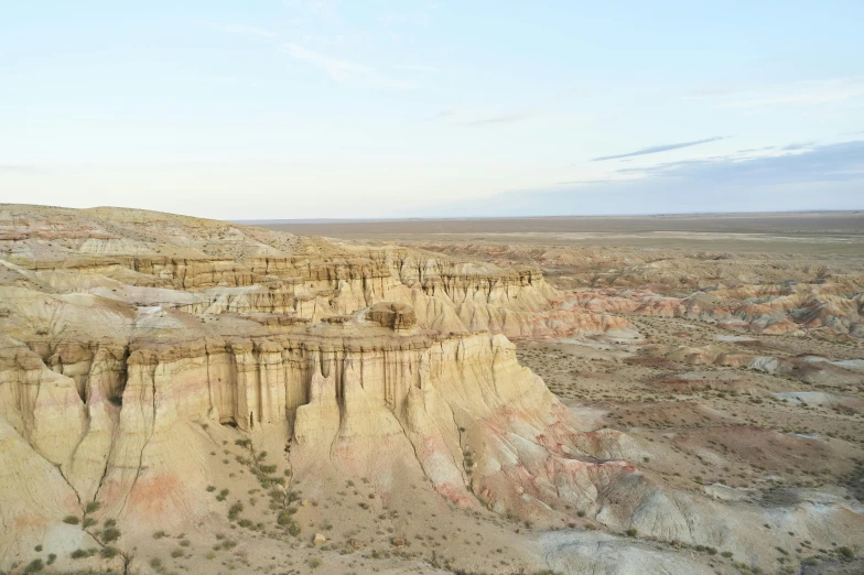 a large rock formation in the middle of a desert, unsplash contest winner, land art, white wall complex, aerial footage, cliff side at dusk, taken in the late 2010s