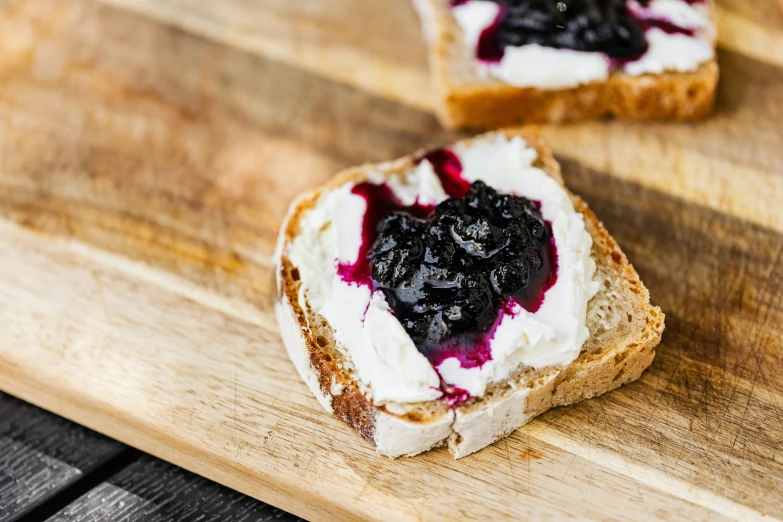 two pieces of bread sitting on top of a wooden cutting board, a portrait, unsplash, blueberry, whipped cream on top, background image, artoast8p