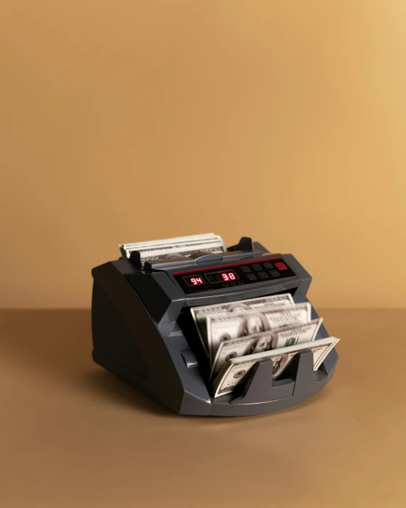 a money counting machine sitting on top of a table, by Julia Pishtar, high quality product photo, small, tan, thumbnail