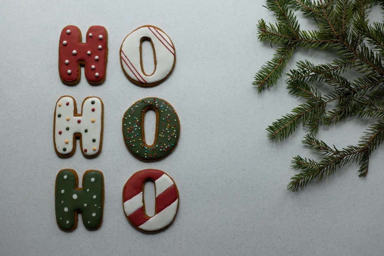 a number of decorated cookies next to a christmas tree, inspired by Ernest William Christmas, pexels, graffiti, perfect letters, on grey background, oh no, background image