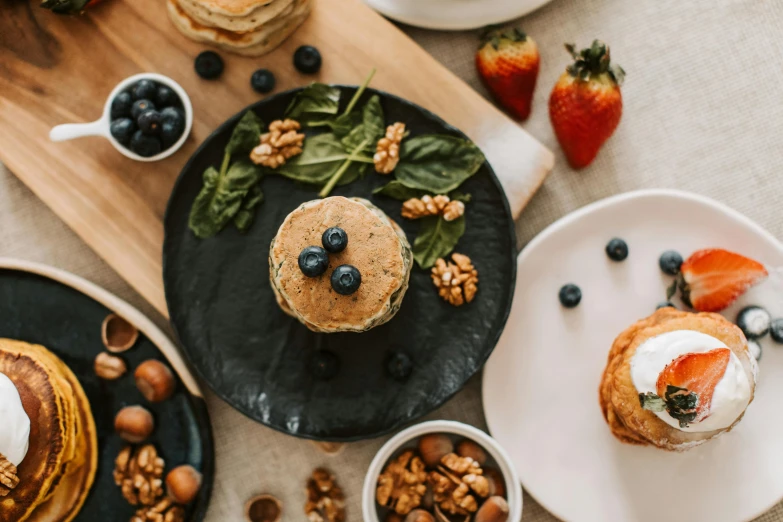 a number of plates of food on a table, a still life, by Emma Andijewska, trending on pexels, living food adorable pancake, blueberries on the side, basil gogos, thumbnail