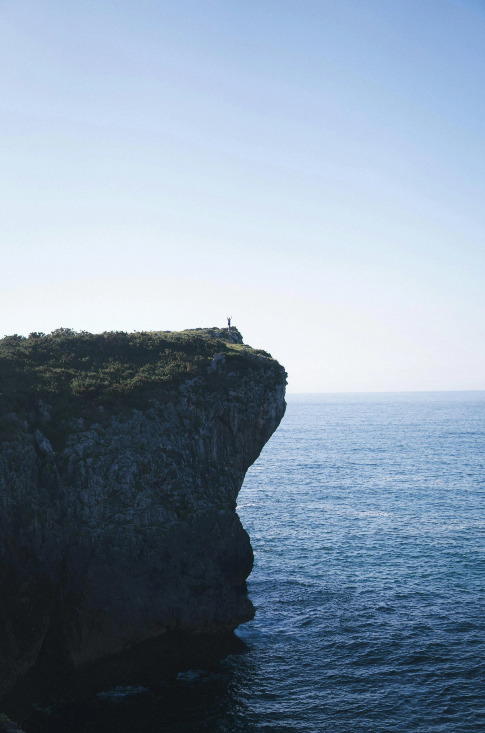 a man standing on top of a cliff next to the ocean, les nabis, slightly minimal, hestiasula head, blue