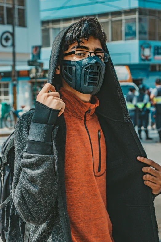 a man wearing a mask on a city street, unsplash contest winner, model is wearing techtical vest, bio - mech face, schools, chilean