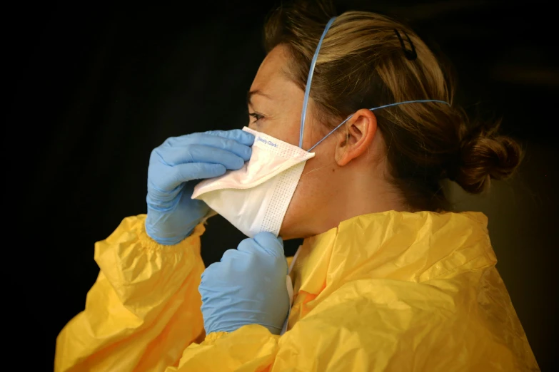 a woman in a yellow jacket and blue gloves, pexels contest winner, plasticien, wearing a white hospital gown, coronavirus, respiratory flap, head down