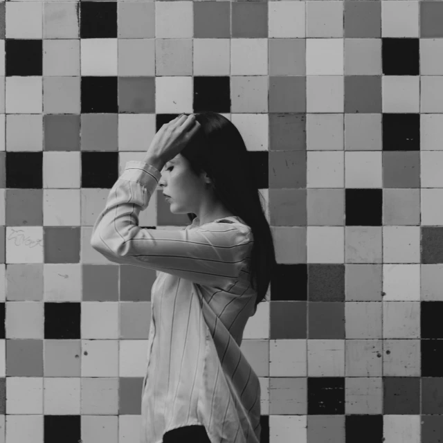 a woman standing in front of a tiled wall, a black and white photo, pexels contest winner, aestheticism, greeting hand on head, korean woman, 15081959 21121991 01012000 4k, squares