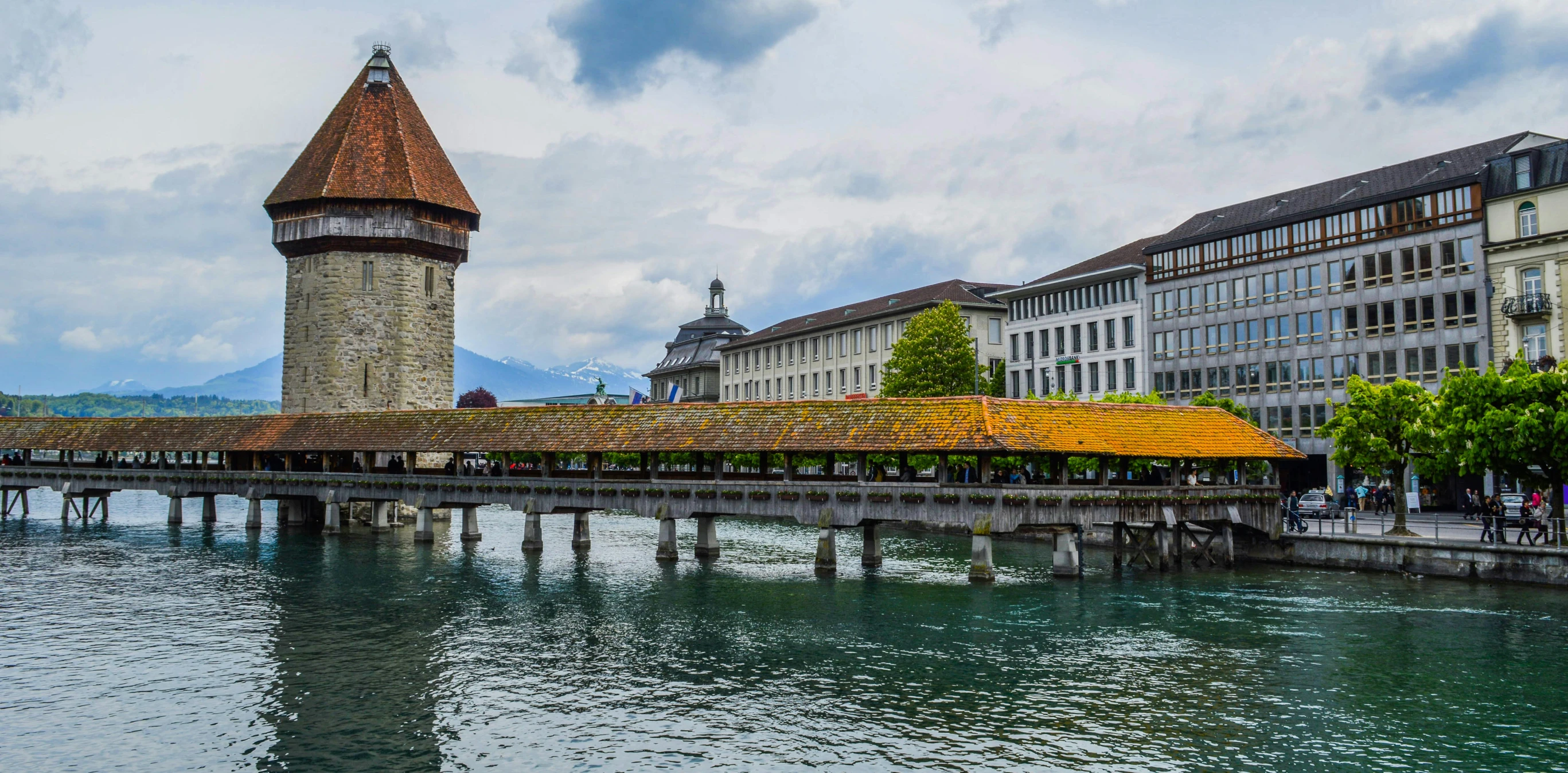 a bridge over a body of water with buildings in the background, inspired by Karl Stauffer-Bern, pexels contest winner, renaissance, thatched roofs, brutalist buildings tower over, square, a colorful