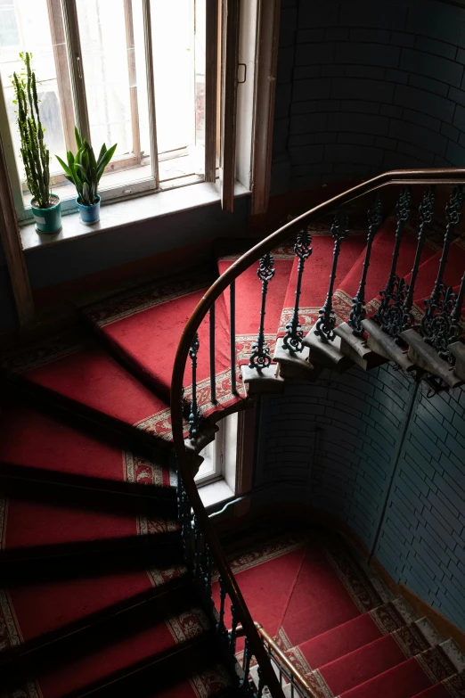 a spiral staircase next to a window in a building, inspired by Elsa Bleda, pexels contest winner, art nouveau, red carpeted floor, 2 5 6 x 2 5 6 pixels, in legnica city hall, apartment of an art student