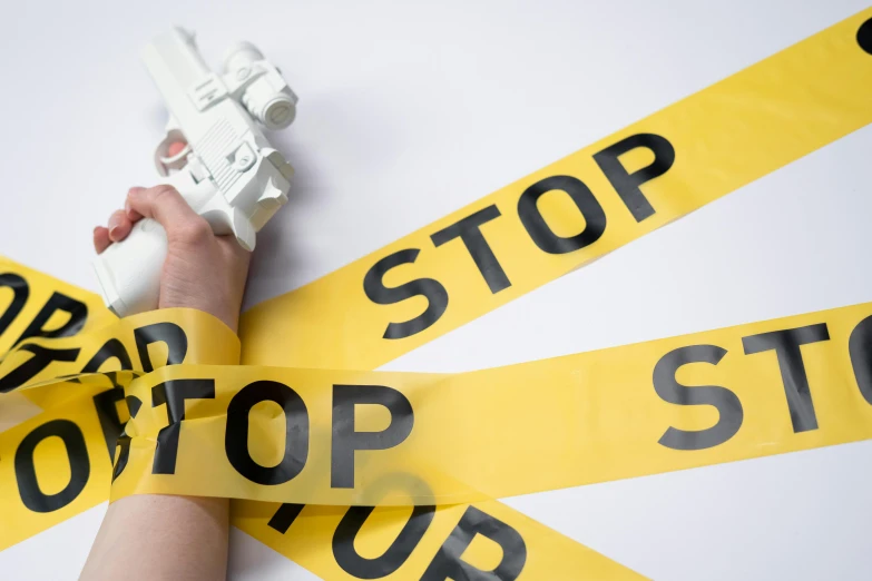 a close up of a person holding a paper gun, a picture, stop sign, white ribbon, getty images proshot, high quality photo