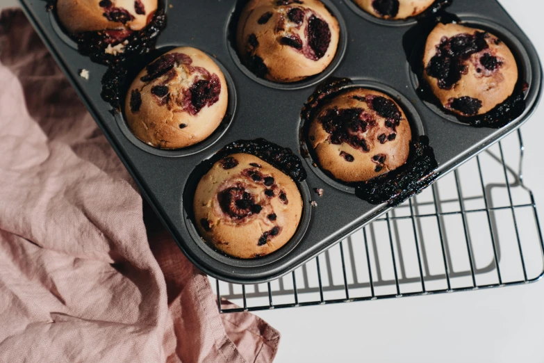 muffins in a muffin pan on a cooling rack, by Emma Andijewska, trending on pexels, squashed berry stains, 🦩🪐🐞👩🏻🦳, small freckles, male and female