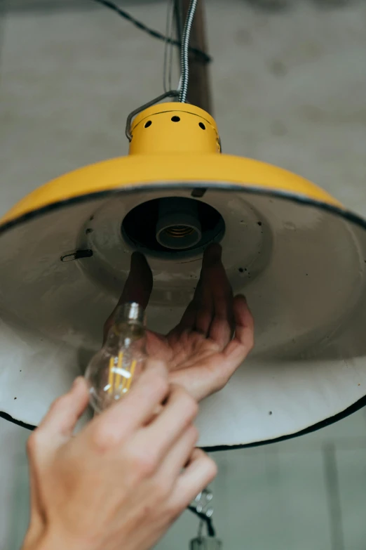 a close up of a person holding a light, by Adam Marczyński, process art, restomod, turning yellow, in a workshop, light fixtures