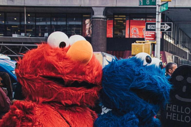 a couple of stuffed animals standing next to each other, a colorized photo, pexels contest winner, elmo as a giant monster, 🚿🗝📝, time square, unsplash photo contest winner
