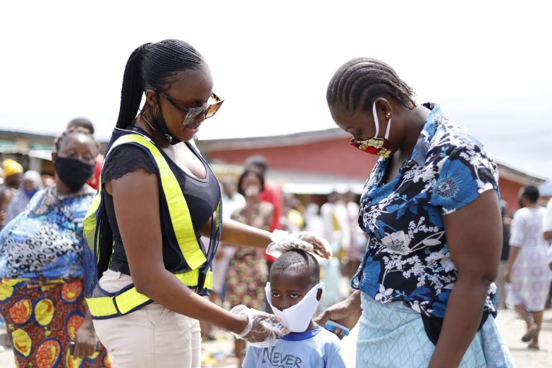 a woman helping a child put on a face mask, happening, epic 3 d omolu, woman holding another woman, official photo, thumbnail