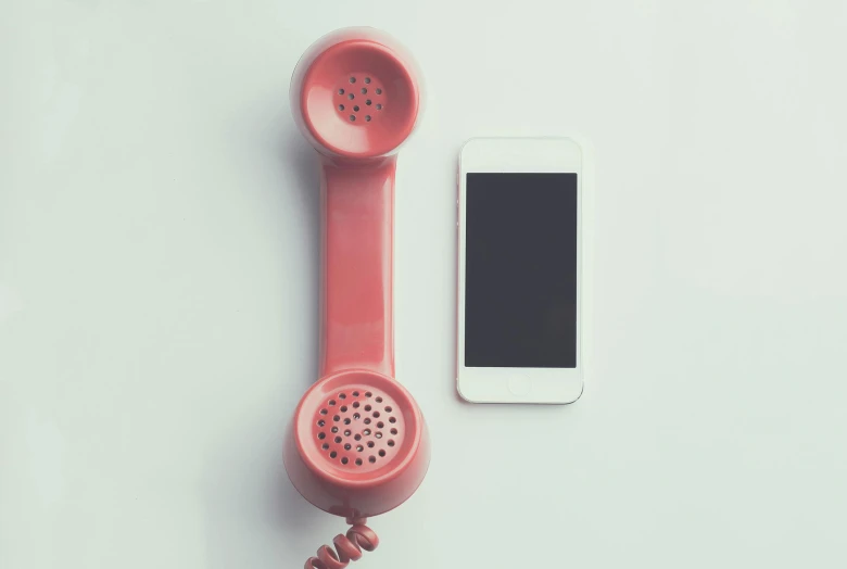 a phone sitting on top of a table next to a red telephone receiver, a photo, trending on pexels, modernism, ((pink)), on a gray background, frank moth, dingy