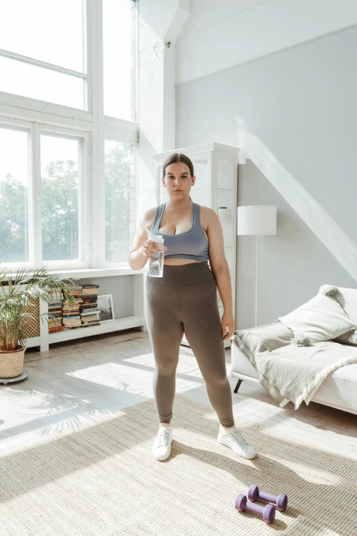 a woman standing in a living room holding a glass of water, by Matija Jama, happening, wearing fitness gear, curvy build, lunging at camera :4, profile image