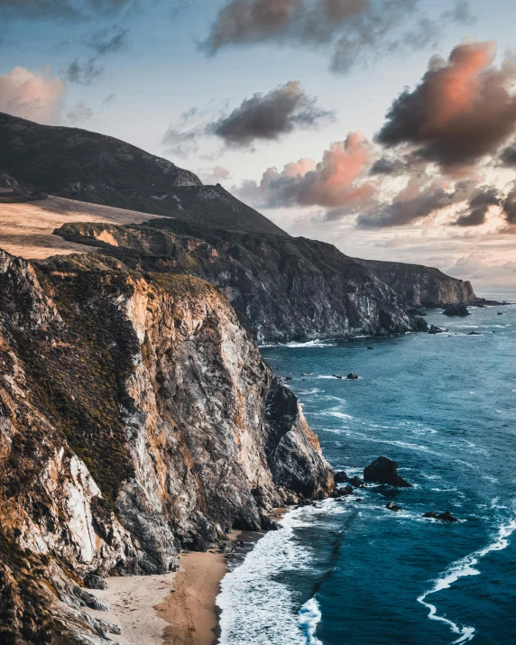 a beach next to the ocean under a cloudy sky, pexels contest winner, renaissance, steep cliffs, sunset in a valley, thumbnail, california coast