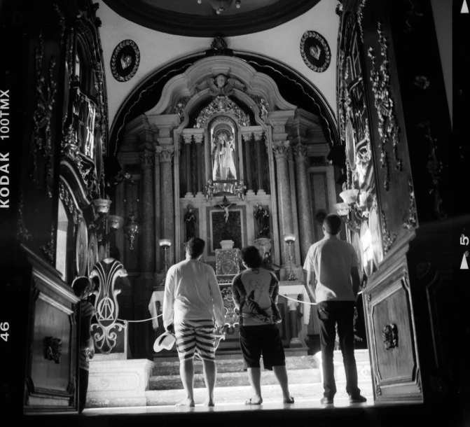 a group of people standing in front of a church, a black and white photo, by Giorgio Cavallon, altar, salvador, memories, brightly lit