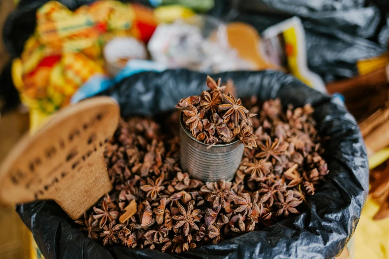 a bag of star anise sitting on top of a table, by Daniel Lieske, pexels contest winner, hurufiyya, tins of food on the floor, licorice allsort filling, thumbnail, brown flowers