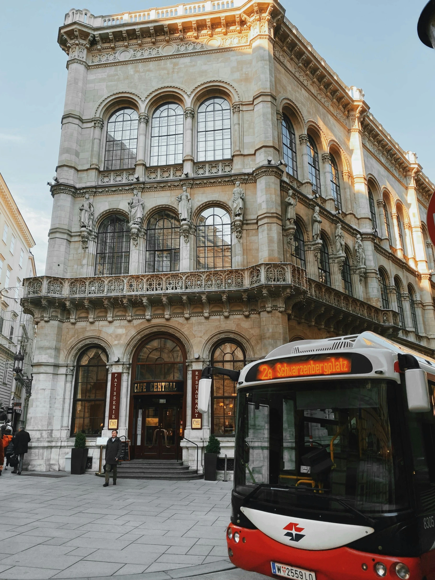 a red and white bus parked in front of a building, by Emma Andijewska, pexels contest winner, viennese actionism, golden glow, gothic building style, thumbnail, multiple stories