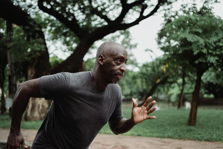 a man running with a frisbee in his hand, inspired by Ma Quan, pexels contest winner, happening, lance reddick, depressed dramatic bicep pose, in a park, a wooden