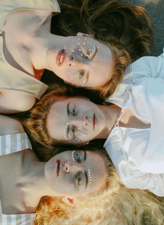 a group of young women laying on top of a bed, inspired by Elsa Bleda, trending on pexels, photorealism, white facepaint, three moons, sadie sink, clean symmetrical faces