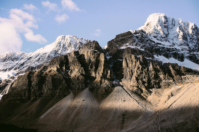 a group of snow covered mountains against a blue sky, trending on unsplash, les nabis, rocky cliffs, banff national park, light and dark, conde nast traveler photo